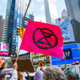 The Extinction Rebellion flag raised with a protester on the boat moored in Times Square in the background.